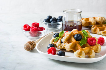 Traditional belgian waffles with blueberries and raspberries on white marble
