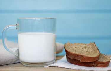 A glass of milk next to a slice of rye bread on the table