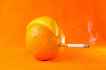 Grapefruit mutant smoking a cigarette on an orange background.