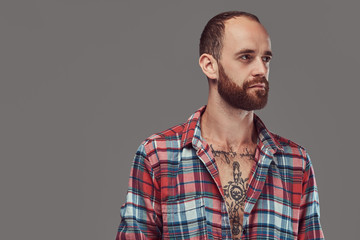 Portrait of a handsome tattooed stylish hipster with a well-trimmed beard in a flannel shirt, posing in a studio.