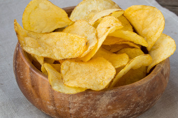 Delicious crispy potato chips in an old wooden bowl
