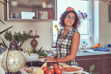Charming curly Hispanic girl cooking in her kitchen.