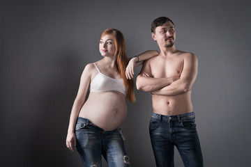 Husband and pregnant wife on gray background