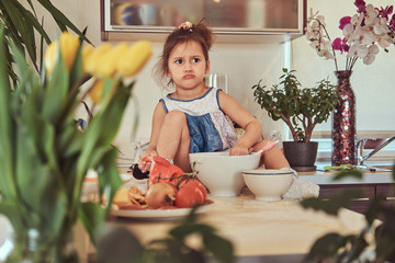 Sweet little cute girl learns to cook a meal in the kitchen.