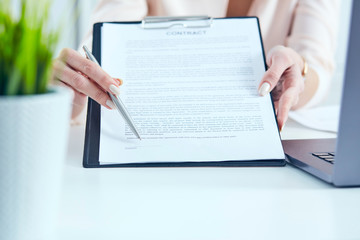 Young businesswoman giving contract for you to sign. Just Hands over the table.