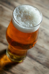 Glass of light beer on a wooden barrel