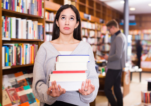 Portrait of adult girl with stack of books