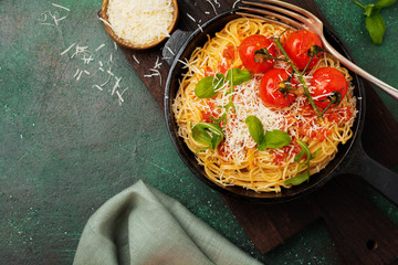Traditional Italian dish of spaghetti with tomato sauce and parmesan cheese in iron frying pan on...