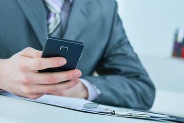 Young business man reading message with smartphone in office.