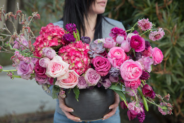 The florist holds beautiful composition of flowers in basket