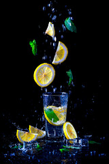 Lemonade with flying lemon and mint, isolated on a black background.