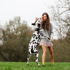young woman plays with an Dalmatian dog outdoors