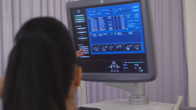 medical center for family planning. two attractive women doctors gynecologists sitting in the ward and looking at the four dimensional ultrasound scan of baby. on the screen of a 2D 3D 3D image of a
