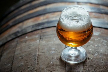 Snifter beer glass on a wooden barrel