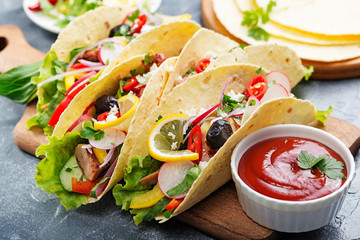 Traditional Mexican tacos with meat and vegetables on gray background .