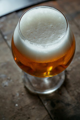 Snifter beer glass on a wooden barrel