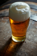 Glass of light beer on a wooden barrel