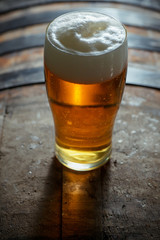Glass of light beer on a wooden barrel