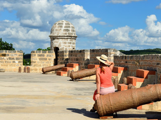 The tourist touring the Jagua fort is sitting on the ancient cannon. Fort built by Spaniards by the Cienfuegos city on Cuba.
