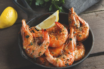 fried roasted shrimps in frying pan with lemon greens parsley garlic - 203972128