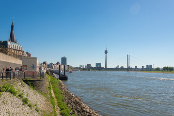 Fototapeta na wymiar Riverside scenery of city Dusseldorf, Germany. View of Rhine River in Düsseldorf. People enjoy outdoor activities along Rhine River bank during summer in Düsseldorf, Germany