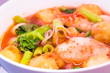 Thai food.Pink seafood flat noodles.Spicy lemongrass flavored soup with pork, chicken on white background.Close up