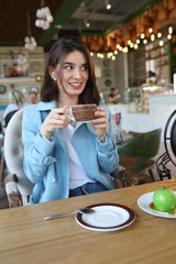 Beautiful young woman sitting in a cafe and drinking coffee.