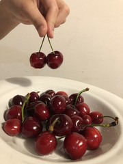 mani di bambina tengono ciliege e piatto