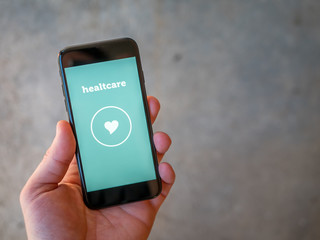Healthcare in mobile phone. A smart app in green pastelle color on grey background.