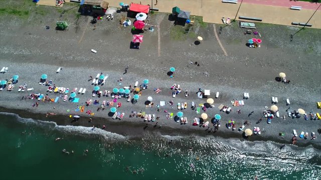 People relaxing on the beach during summer holidays on the beach. Aerial bird eye view of tourists on Batumi's beach, Georgia