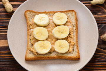 Peanut butter toast with banana slices  on wooden background