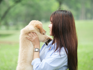 Asian woman playing puppy dog in park