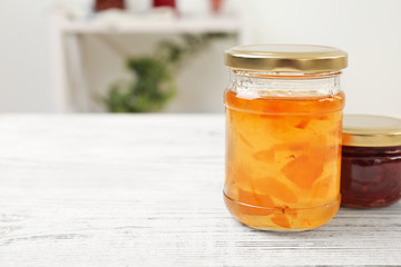 Two jars with tasty sweet jam on wooden table