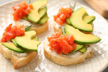Fototapeta na wymiar Tasty sandwiches with fresh sliced salmon fillet and avocado on plate, closeup