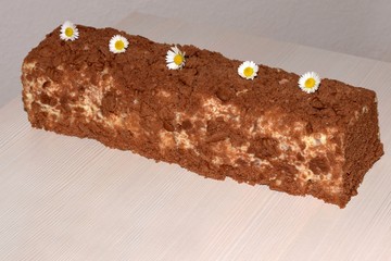 Unbaked layered dessert from light and dark cookies and curd, decorated with daisies