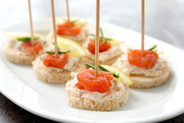 Canapes with fresh sliced salmon fillet on plate, closeup