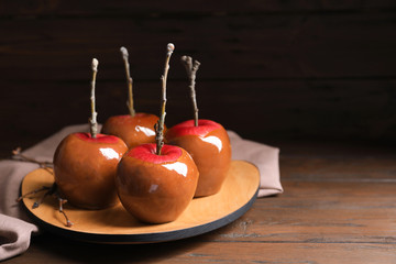 Plate with delicious caramel apples on wooden table