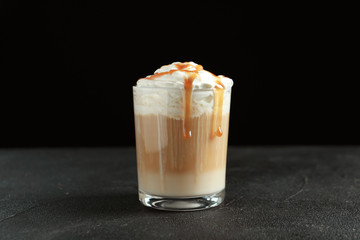 Glass with delicious caramel frappe on table