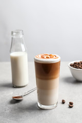 Glass with delicious caramel latte on table