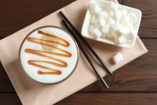 Glass with delicious caramel latte on table