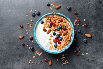 Bowl with yogurt, berries and granola on gray background, top view