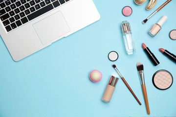 Flat lay composition with laptop and makeup products for woman on color background