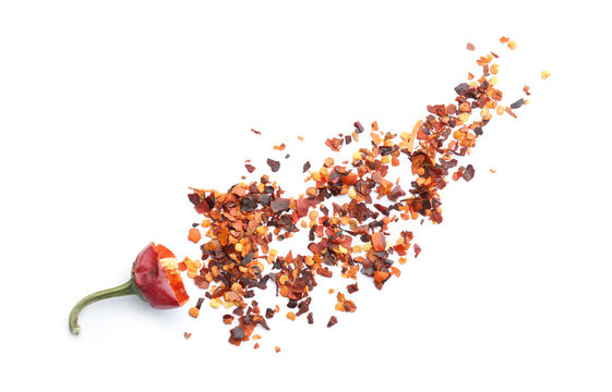 Composition with chili pepper flakes on white background, top view