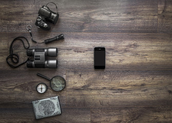 on a dark wooden background passport camera magnifier lantern compass binoculars phone smartphone mobile journey vacation