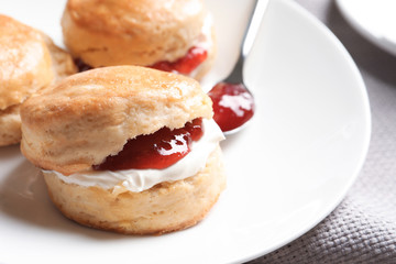 Obraz na płótnie Canvas Tasty scones with clotted cream and jam on plate, closeup