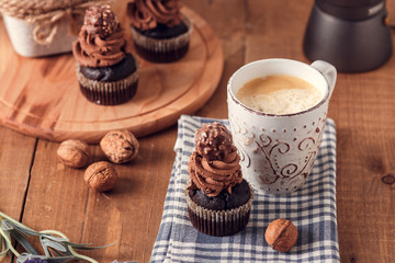 Tasty chocolate cupcakes on wooden board. Cup of coffee. Geyser coffee maker.