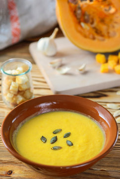 pumpkin cream soup in a clay plate on a wooden table