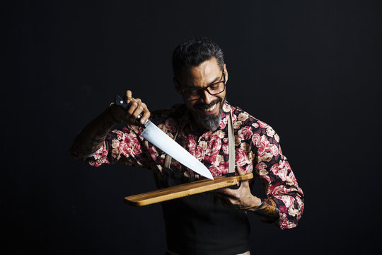 Portrait of a man with cutting board and butcher knife, isolated in a studio background