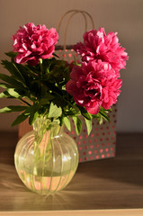 Fresh bouquet of pink peonies peony roses flowers in a vase on table in room. A gift to a mum's day. Sunny day background. Blossom wallpaper. Card, copy space.