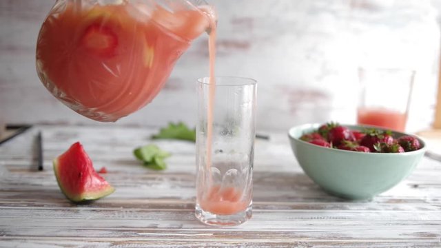 Pouring watermelon and fruit detox water, aqua fresca, 
 in a tall glass, against a white background with ingredients around, high key  tonalty
